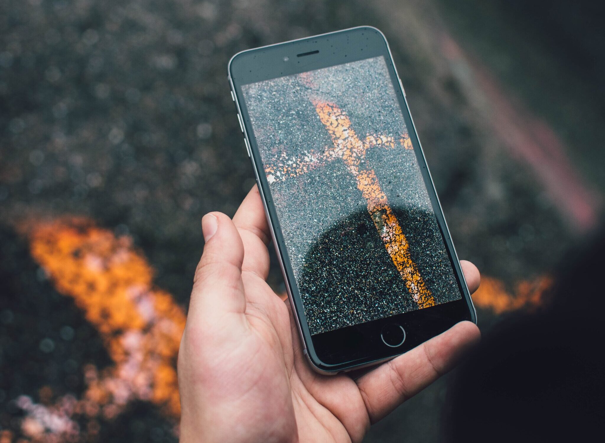 Picture of a phone looking through the phone's camera and showing what appears to be a cross on pavement